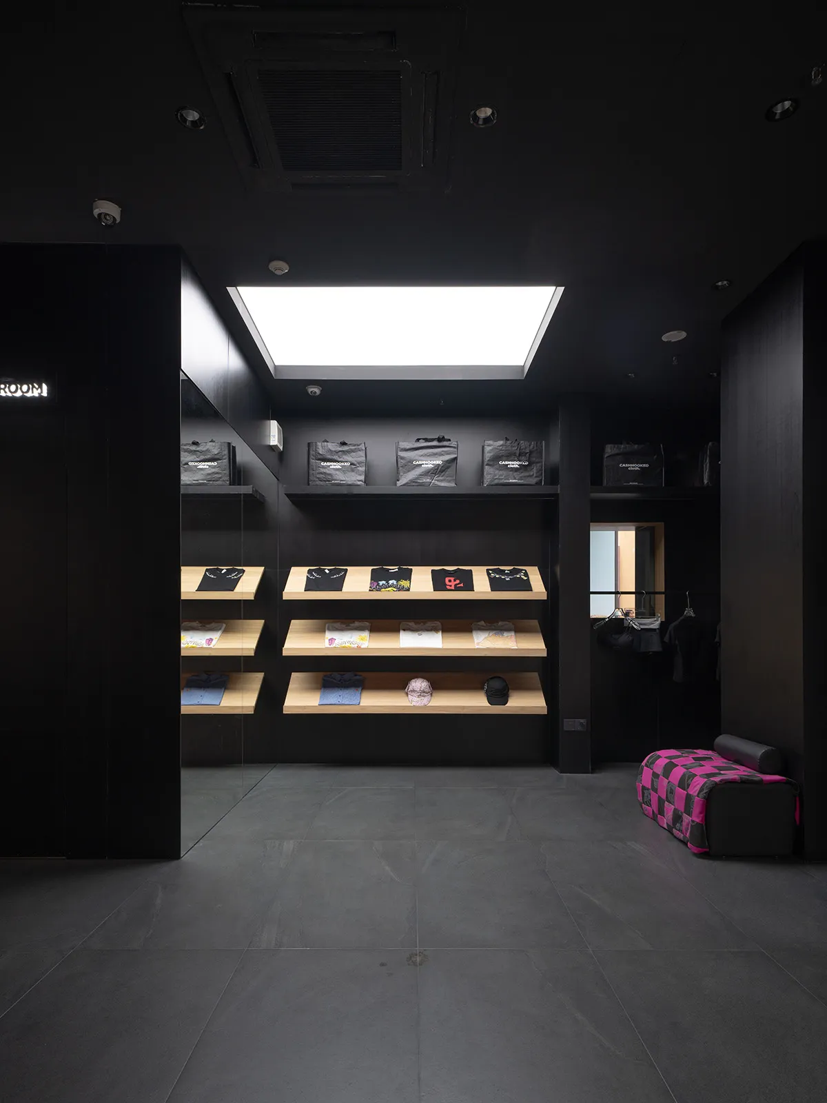 一間時尚現代的零售店,展示衣物於木質層架,並以黑色牆面與素材為特色。