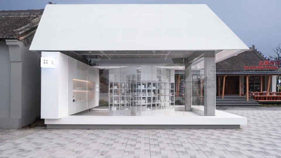 A minimalist storefront with a glass facade and white structural elements.