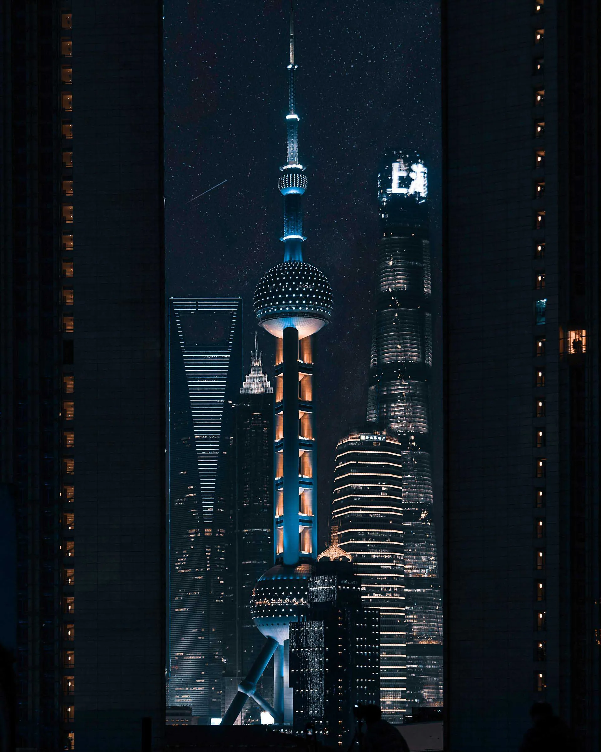 A nighttime cityscape featuring illuminated skyscrapers in Shanghai, China.