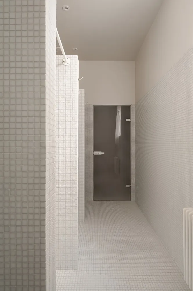 A minimalist bathroom with white tiles and modern design elements.
