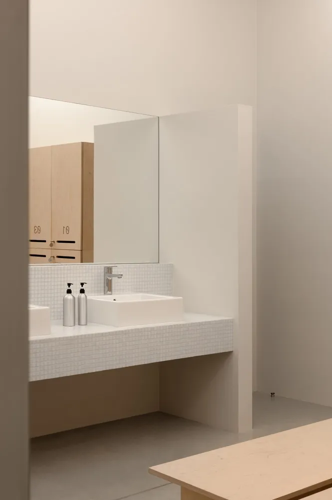 Modern bathroom with white tile, wooden vanity, and metal sink fixture.
