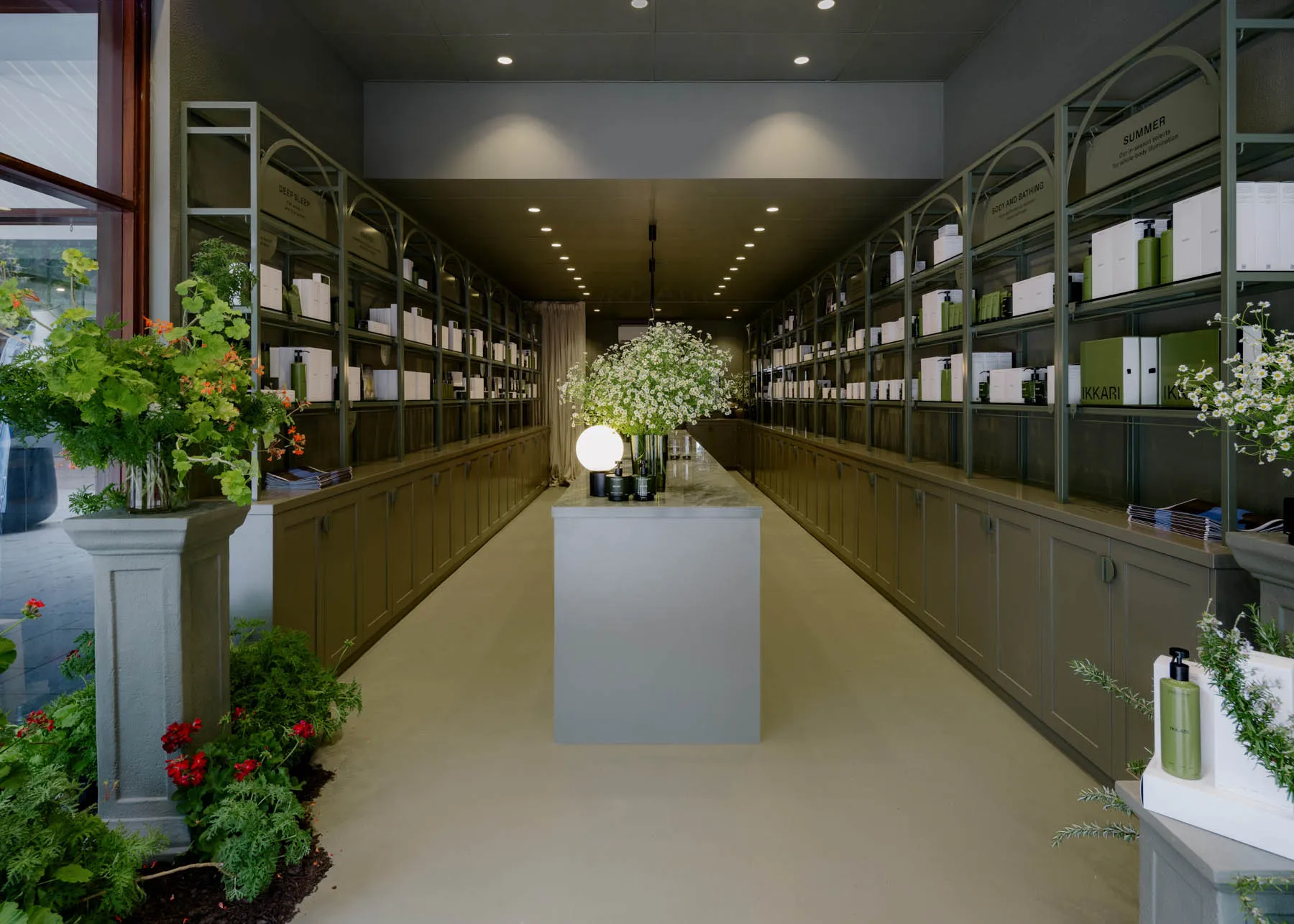 現代零售店面,搭配白色大理石檯面、混凝土地板,以及擺滿商品的混凝土陳列架。