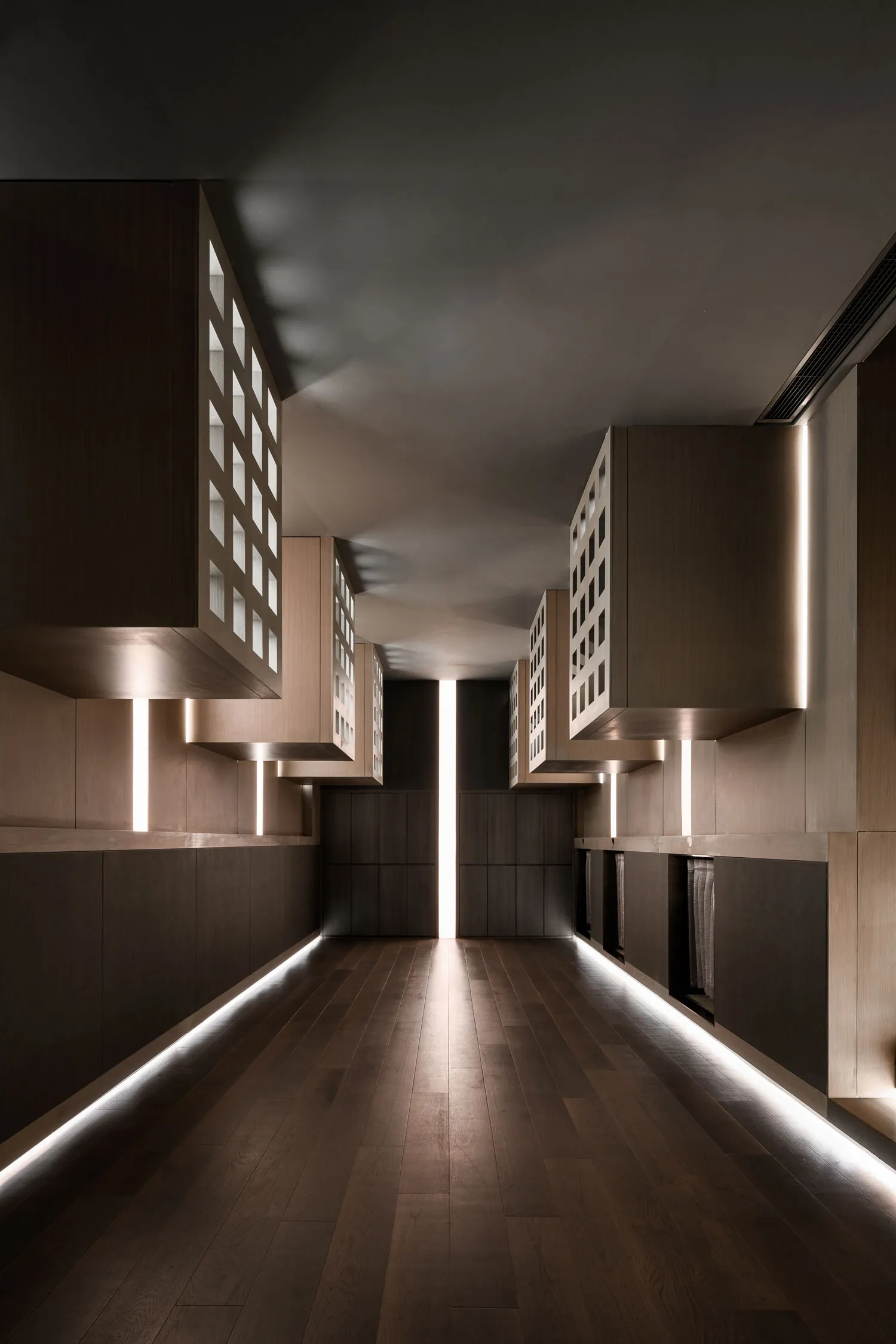 A minimalist corridor featuring wooden panels, metal accents, and illuminated lighting.