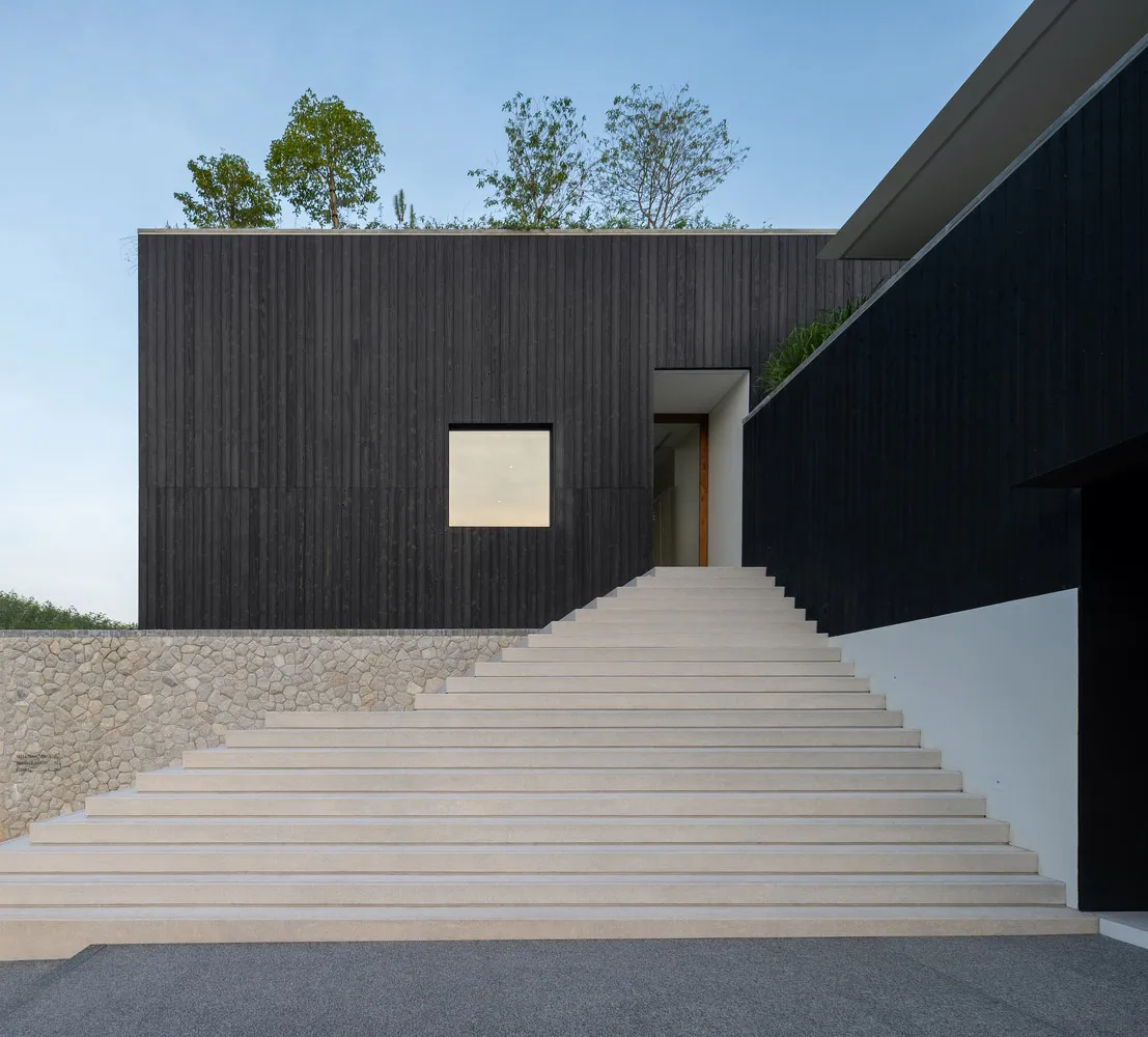 Modern staircase leading up to a building with black walls.