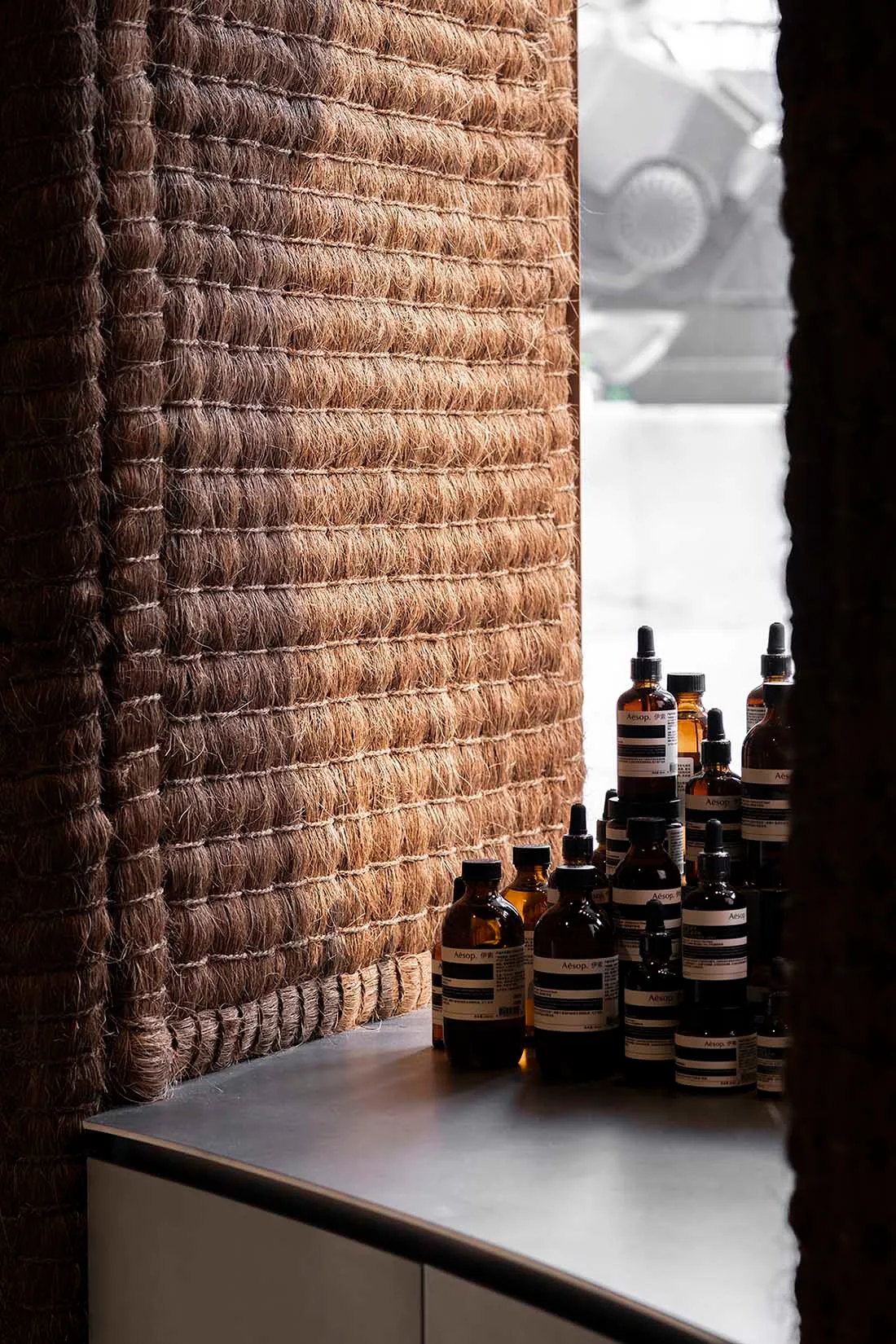 A retail storefront display featuring textured rope and multiple bottles of skincare products.