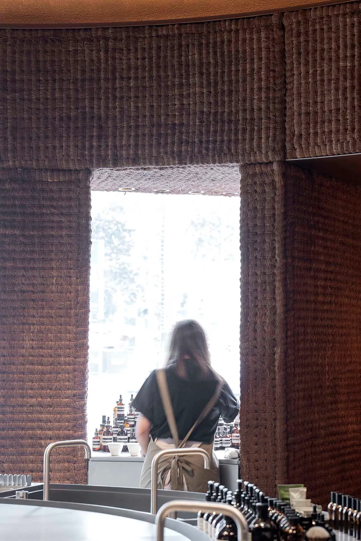 A textured wall paneling restaurant counter with a person standing behind it.