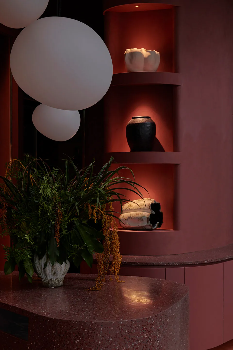 Modern interior design with red shelves displaying ceramic and terrazzo materials.