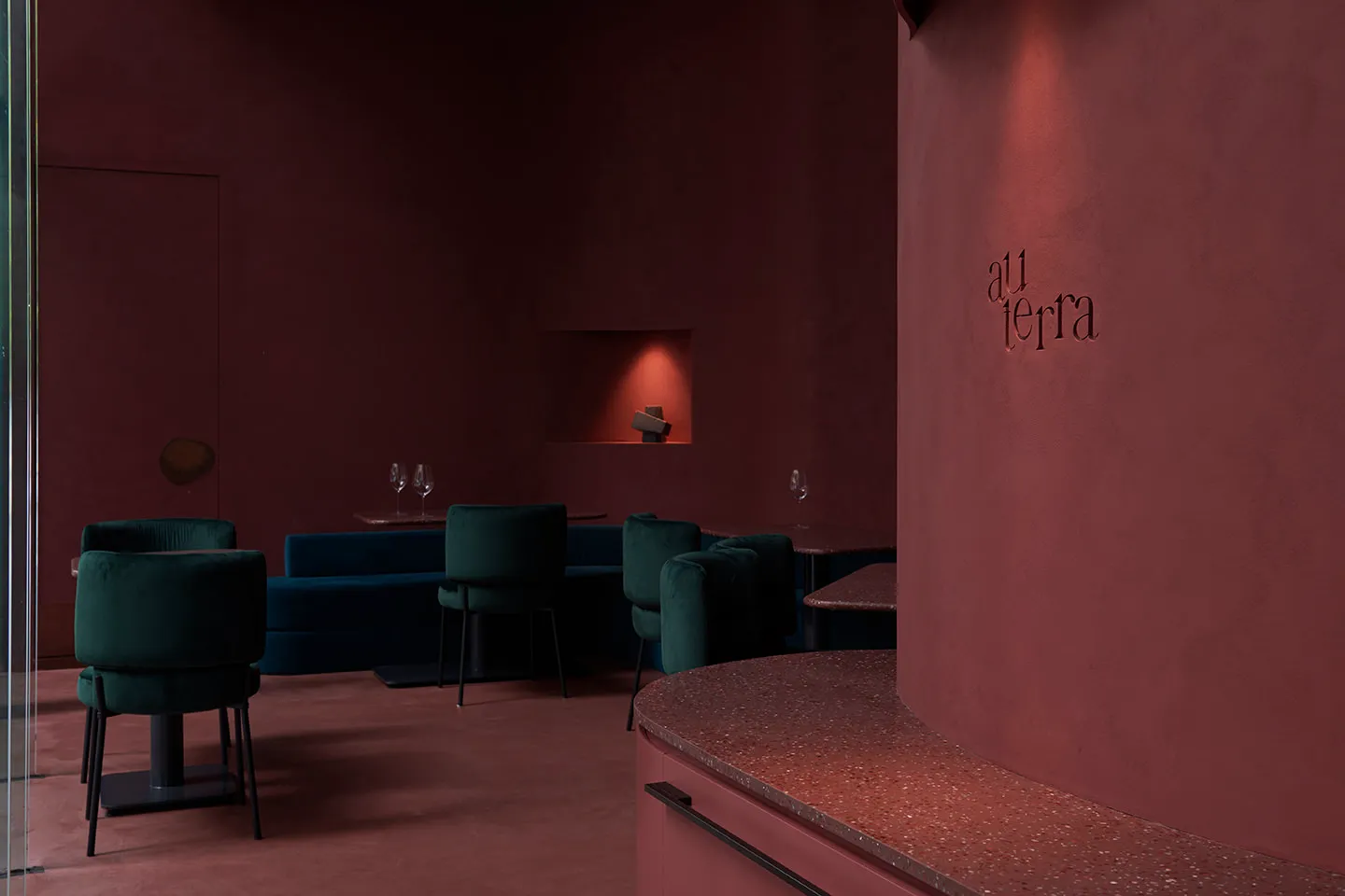 Circular bar area in a modern restaurant with red terrazzo flooring and wooden seating.