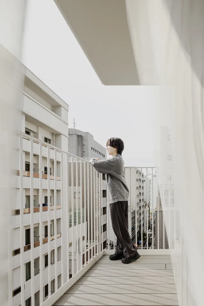 A minimalist balcony with a wooden deck overlooking a cityscape.