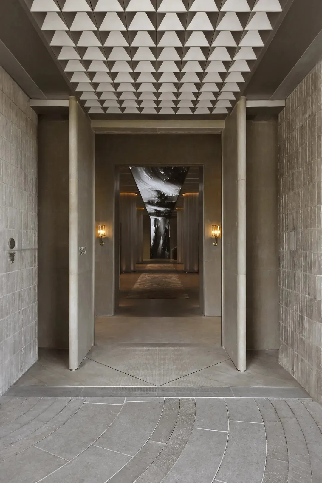 Modern entrance hall featuring a concrete floor and ceiling with geometric patterns.