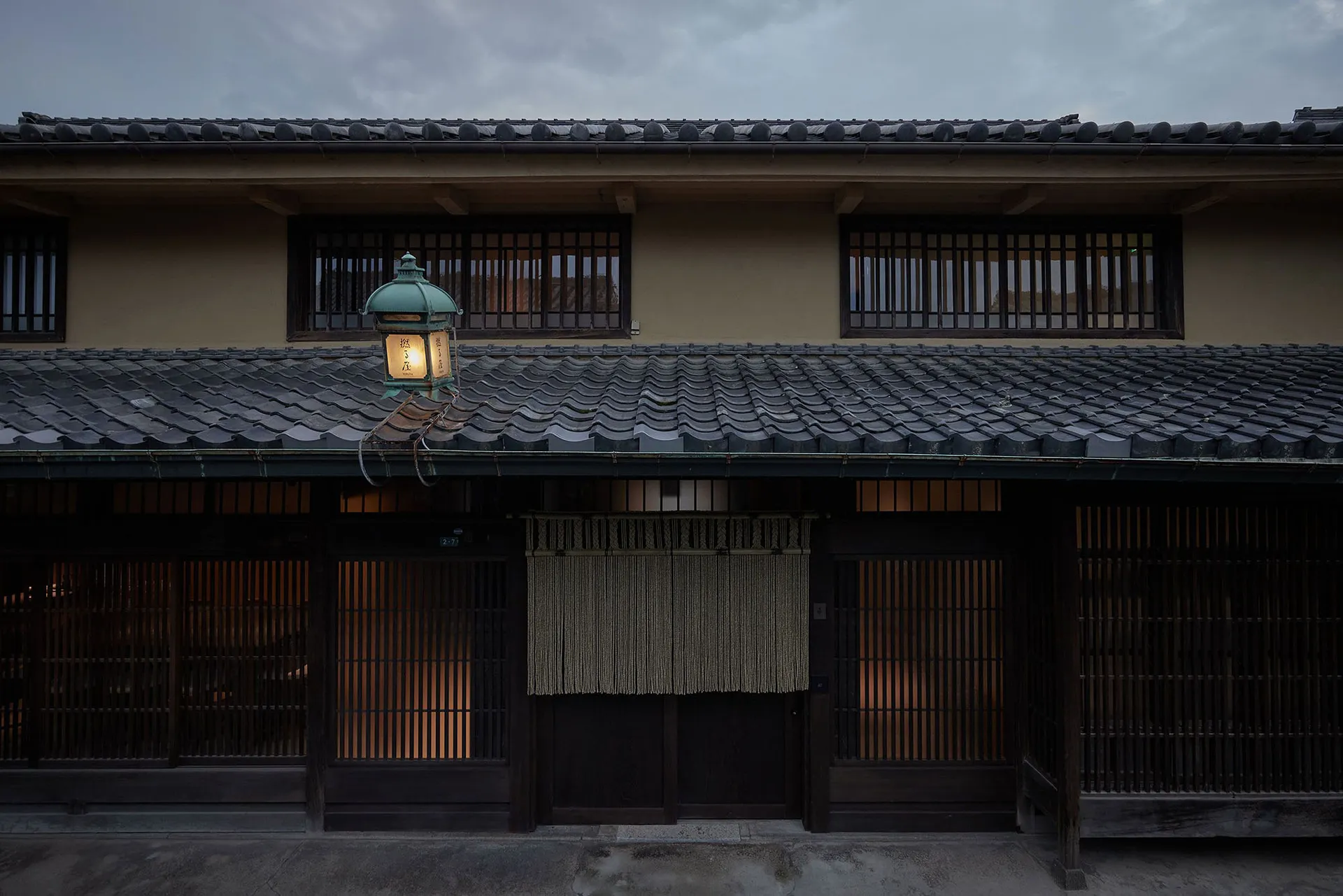 A traditional Japanese building with a grey tiled roof and wooden shutters.