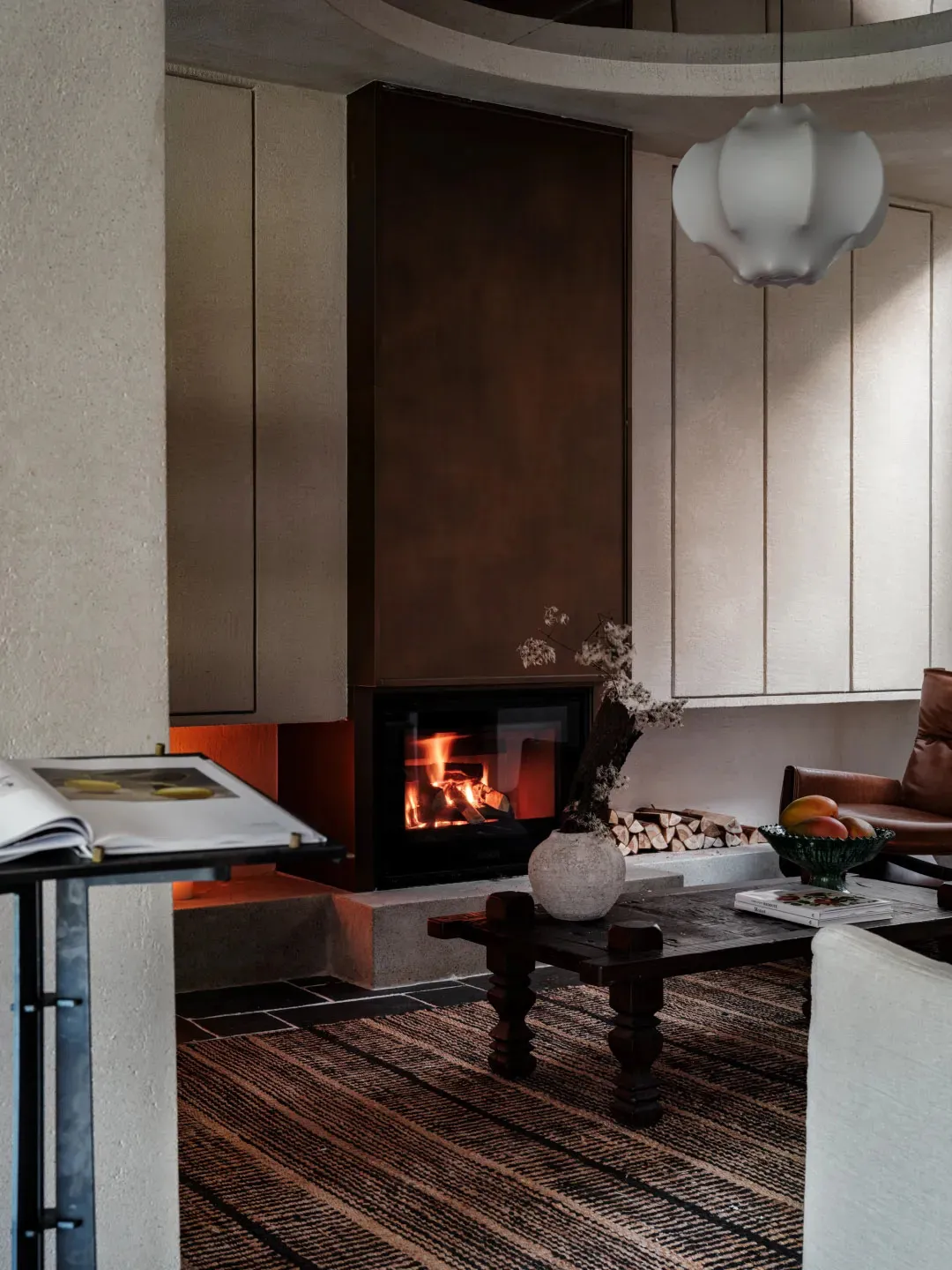 A modern living room with a concrete fireplace, wood accents, and a striped rug.
