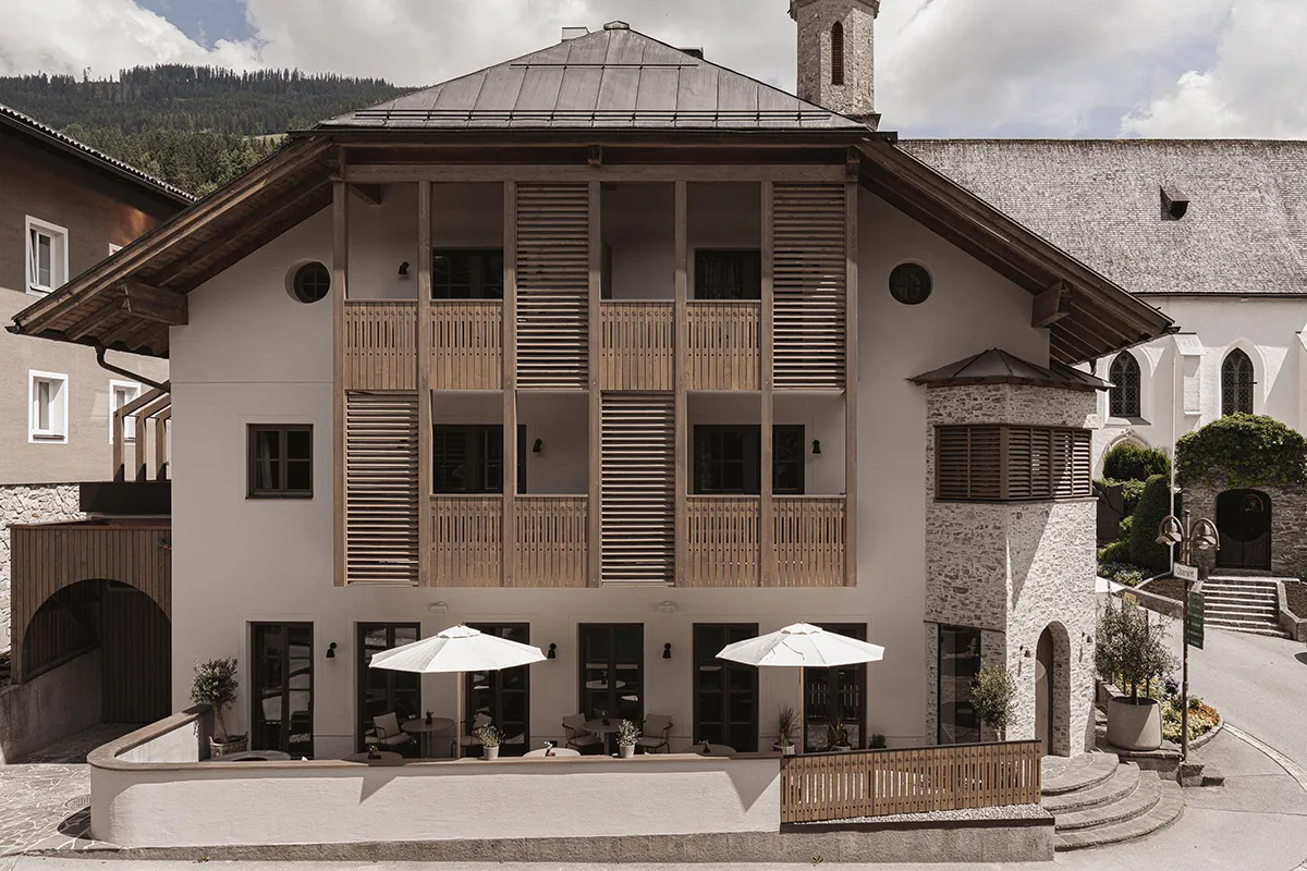 A modern hotel with stone and wooden exterior, featuring exterior balconies and a stone staircase.