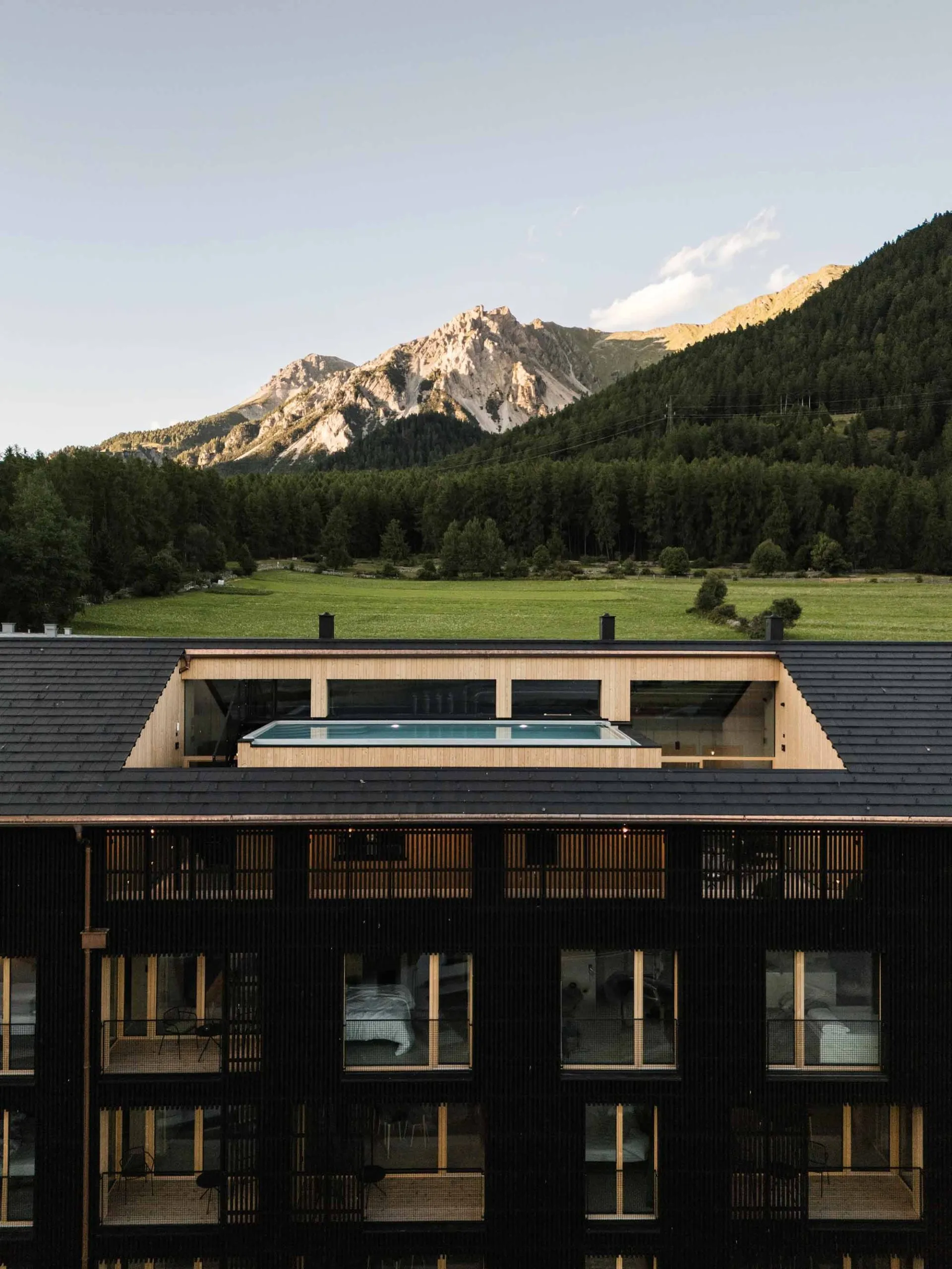 Modern hotel room with black wood walls and a glass area overlooking mountains