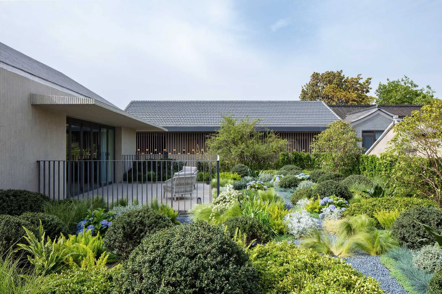 A well-designed modern outdoor space featuring lush green vegetation including ferns, hydrangeas, and other ornamental plants