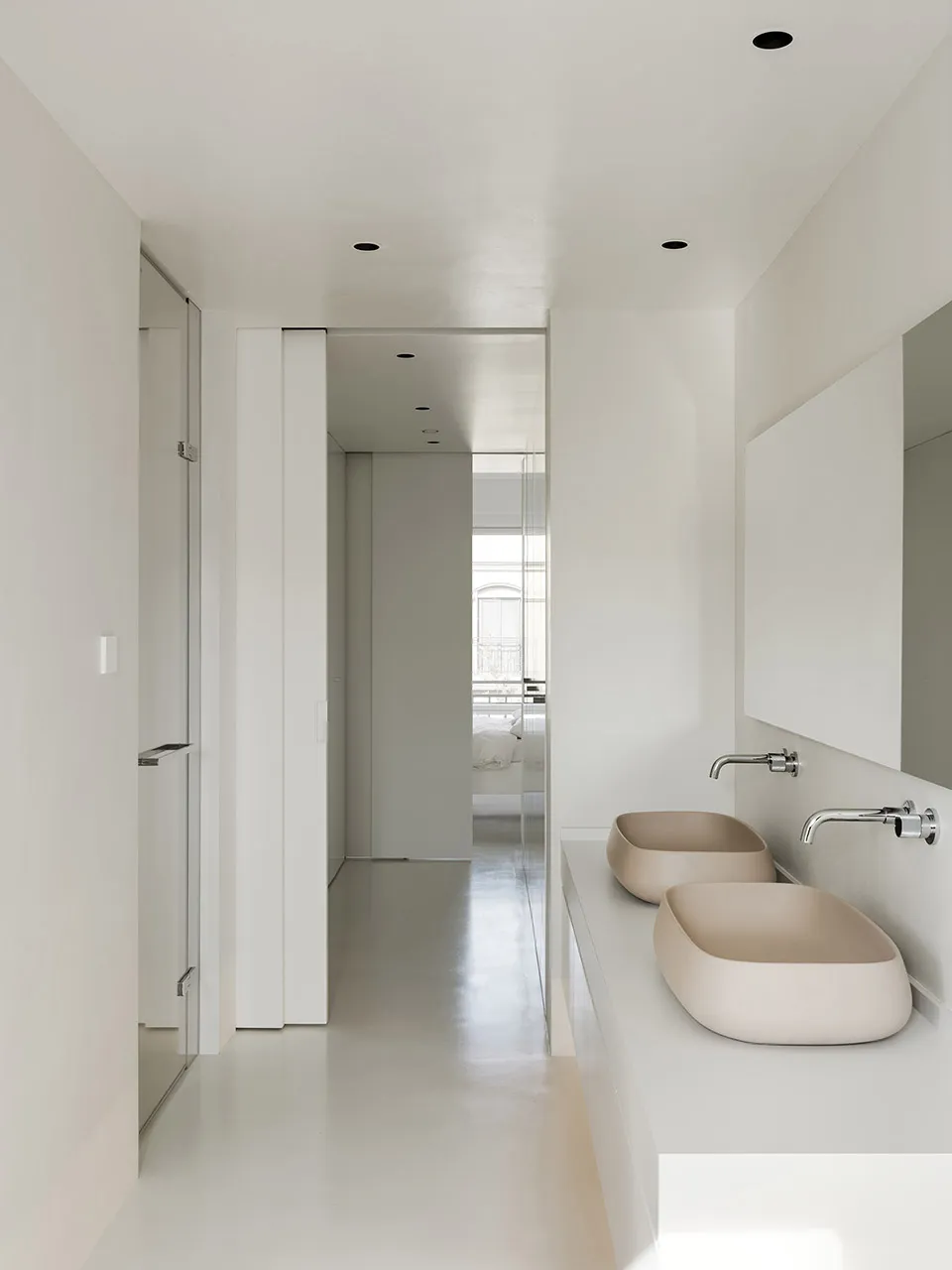 White minimalist bathroom with porcelain sinks and floors.