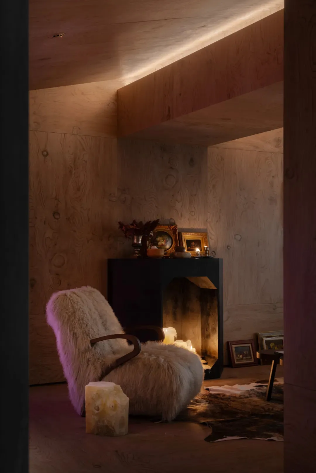 Industrial-style lounge area featuring a wooden armchair, candles, and framed artwork.