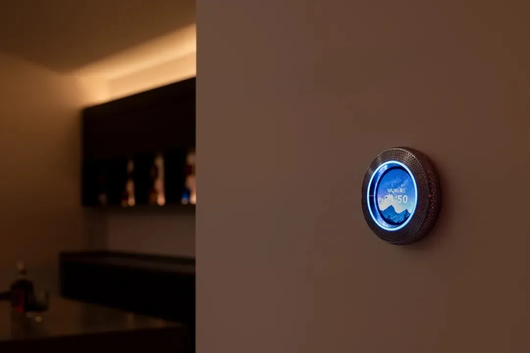 Modern smart home speaker with metallic and glass design, displaying time and temperature.