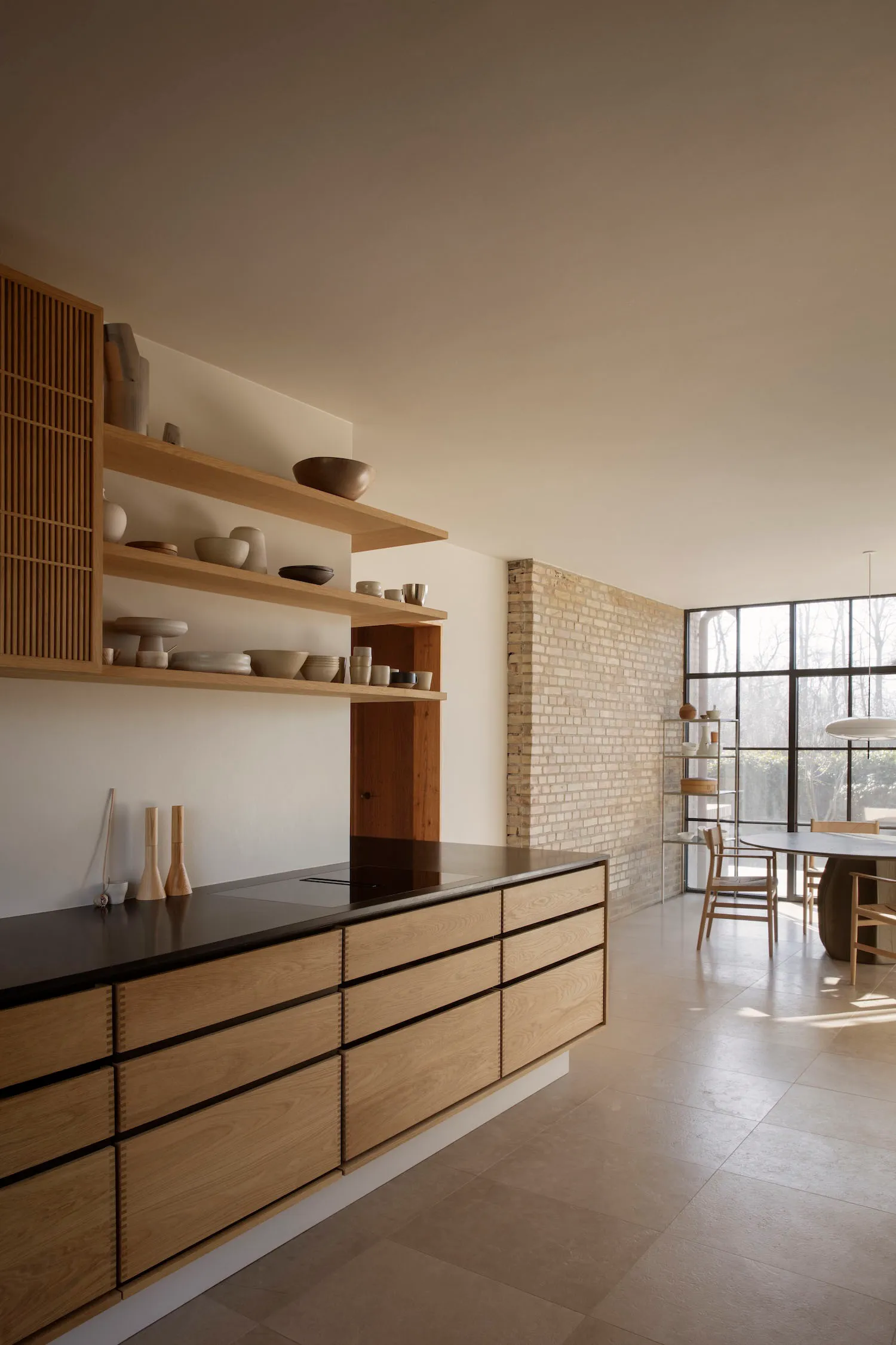 A minimalist residential kitchen featuring an open-plan design with wooden cabinets and shelves.