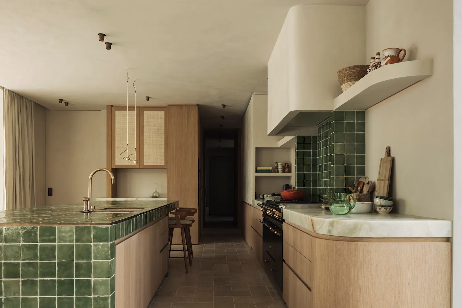 A modern minimalist kitchen with green tiles and a marble countertop, featuring a sleek design and natural lighting.