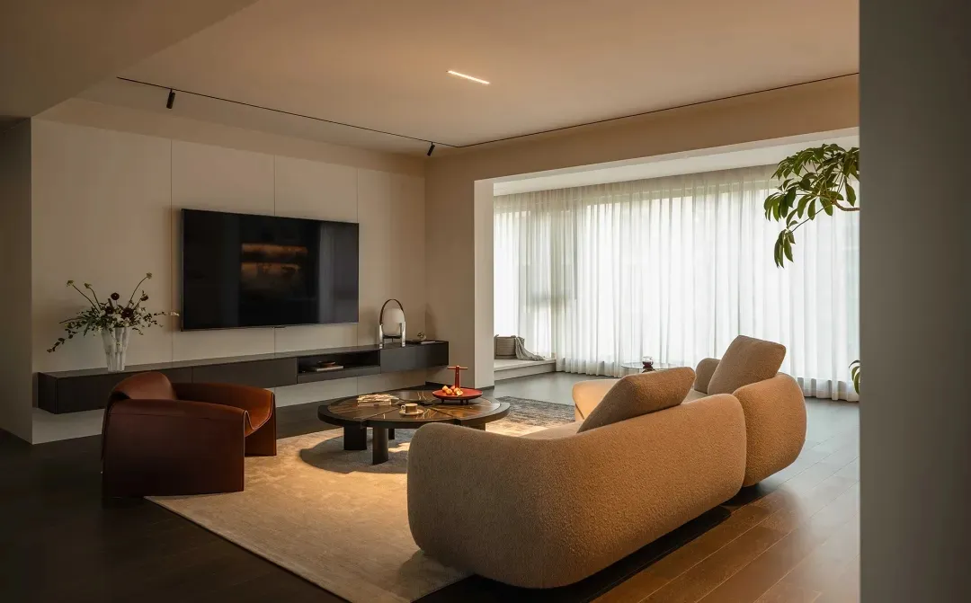 A minimalist living room featuring wooden flooring, fabric furniture, and glass elements.