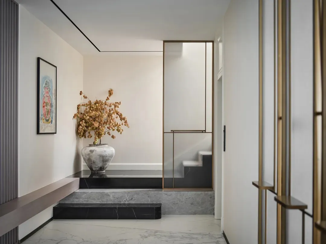 A modern entrance featuring a marble step, concrete floor, and brass frame.