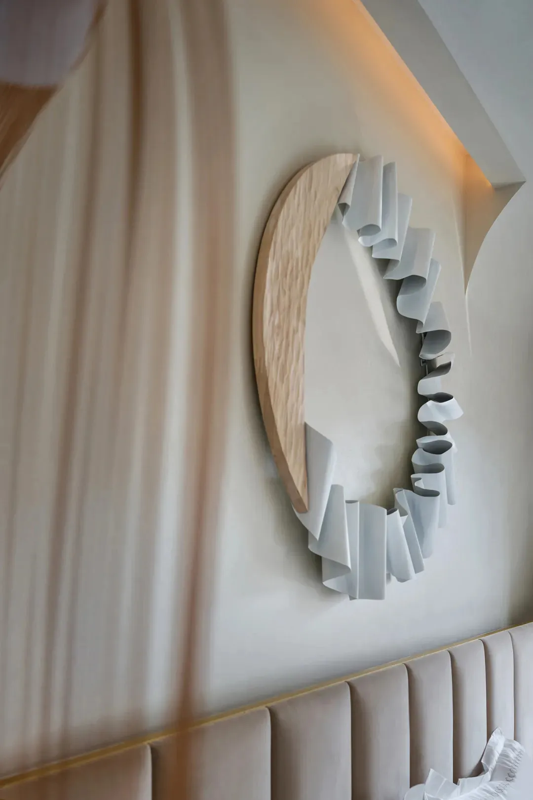 A modern, curved wooden wall object with white ribbons attached.