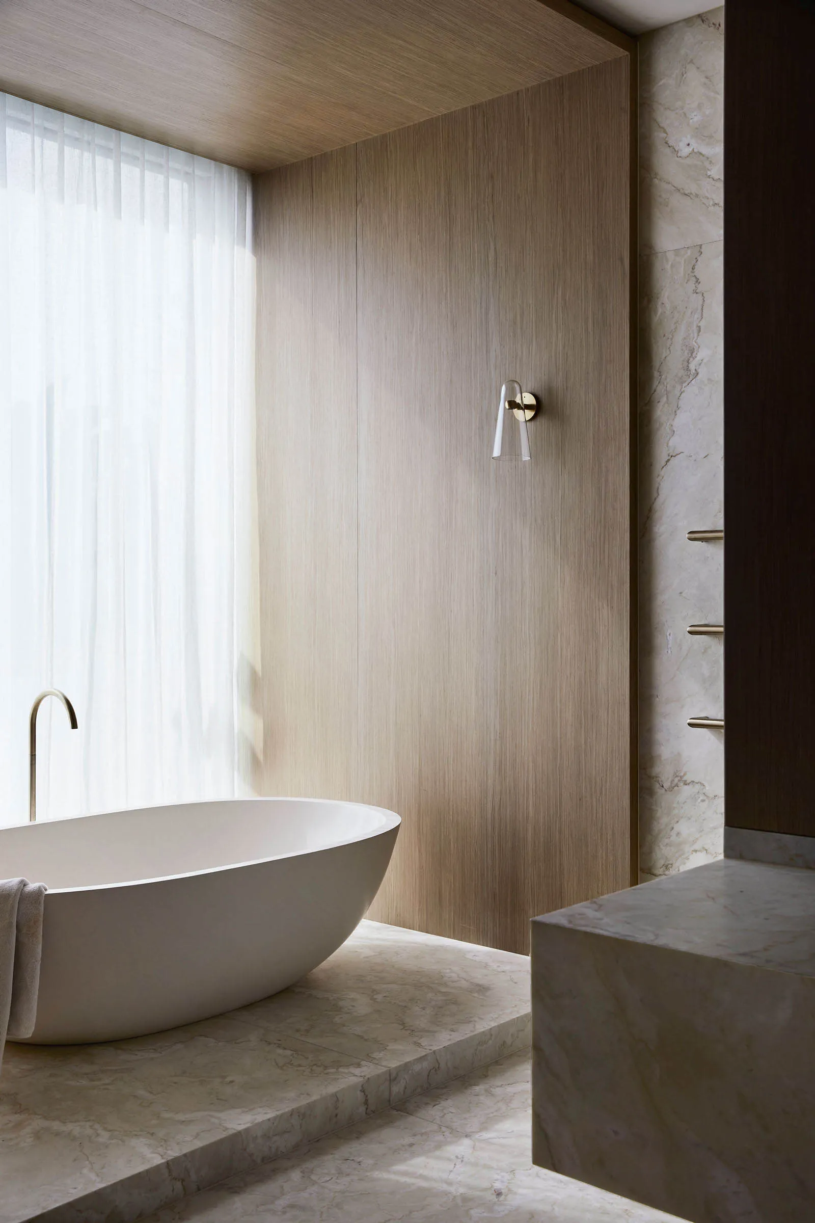 Modern bathroom interior with a freestanding bathtub, marble walls, and floor.