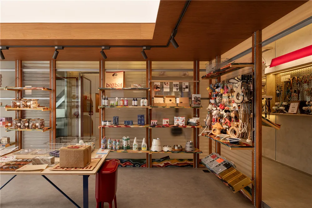 A retail store with wooden shelves displaying pet supplies, including various toys and accessories hanging on metal hooks.