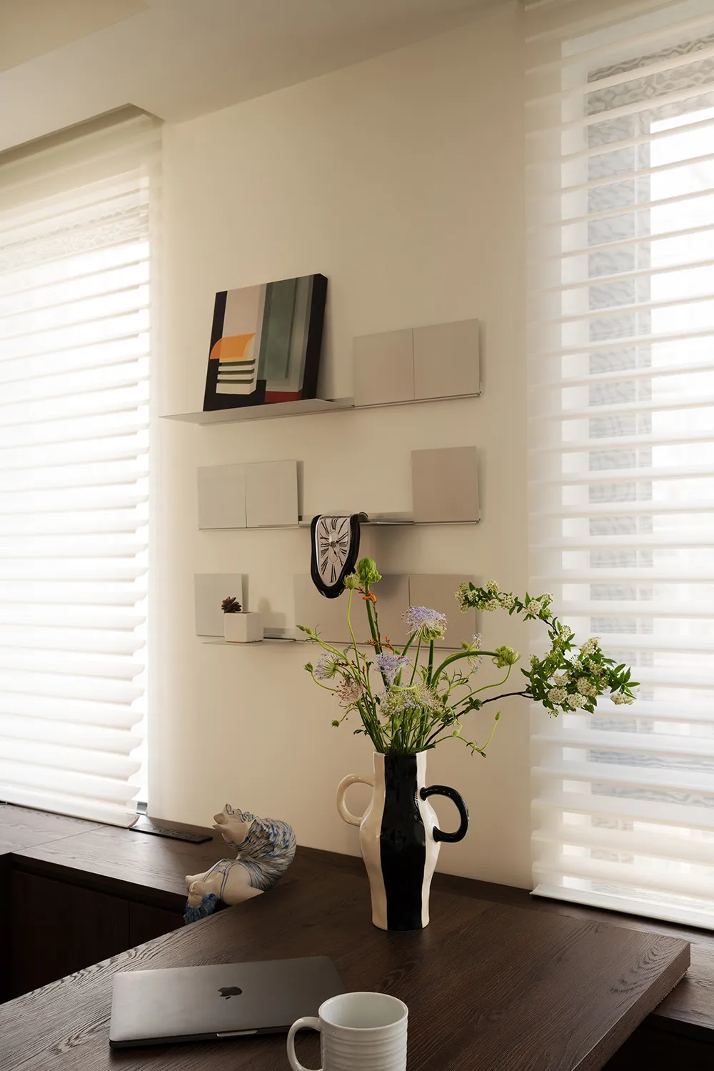 A minimalist interior design featuring a wooden desk with a ceramic figurine and modern decor elements.