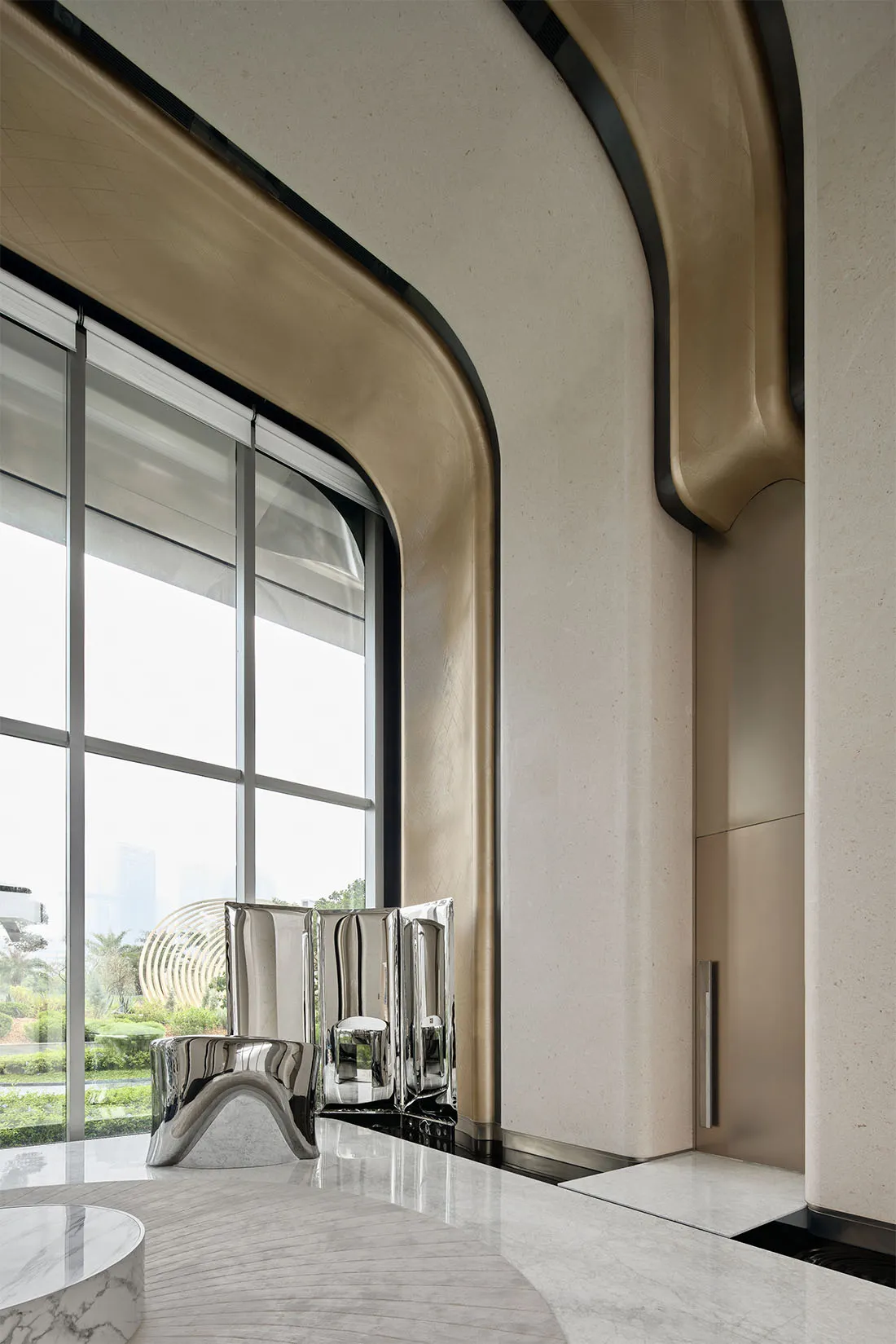 Modern hotel lobby with marble walls and floor, featuring sleek furniture and large windows.