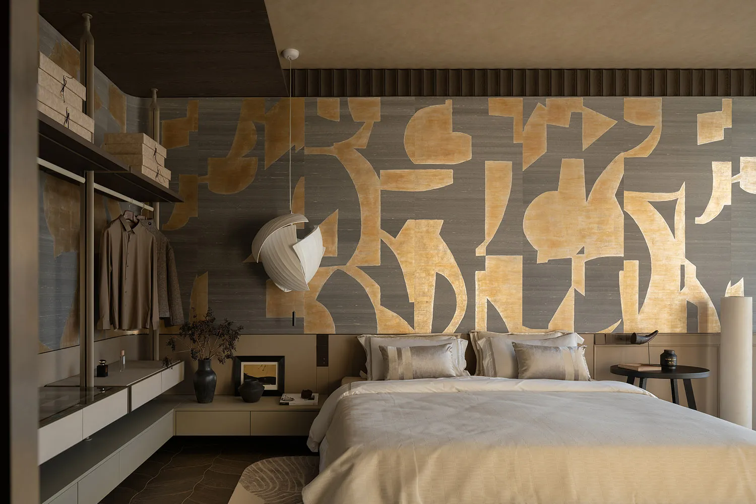 Modern bedroom featuring a patterned wall with abstract shapes in shades of gold and gray, a bed with striped pillows and a r