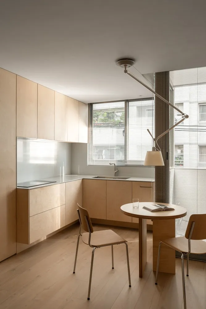 Modern minimalist kitchen featuring wood cabinets and a glass backsplash.