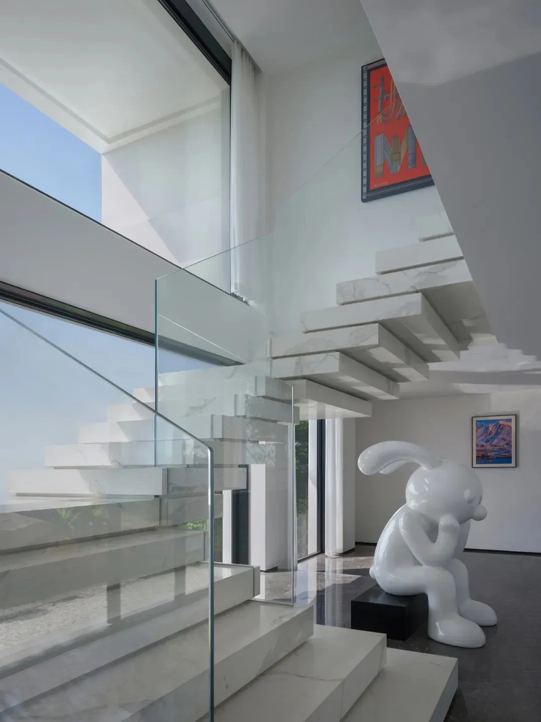 Modern white marble and glass staircase in an interior design setting.