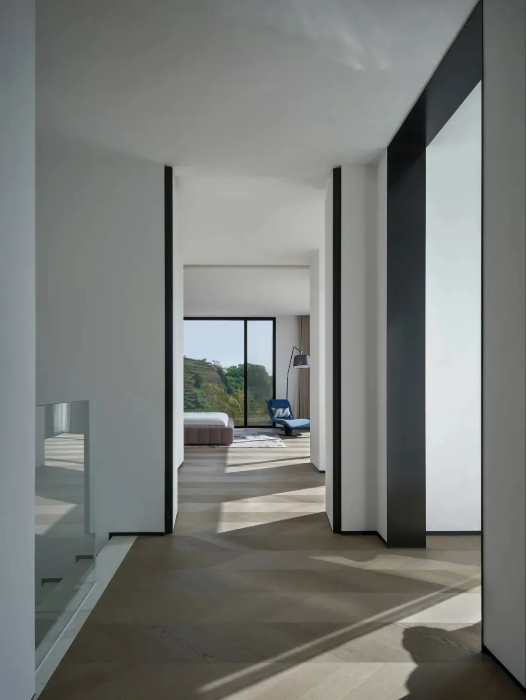 A minimalist bedroom with a wooden floor and a bed.