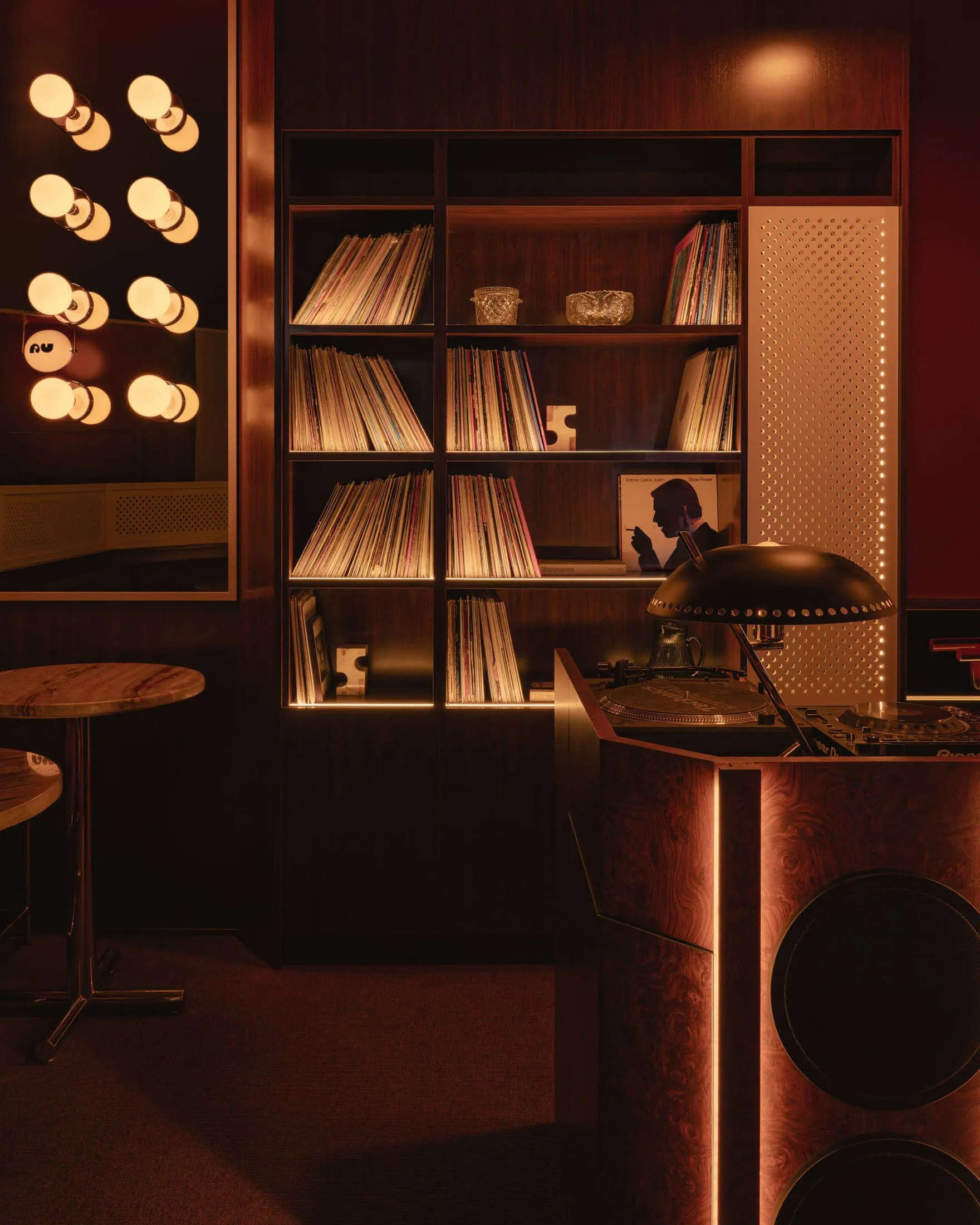 A modern music room with a library of vinyl records on wooden shelves and a turntable on a wooden cabinet.
