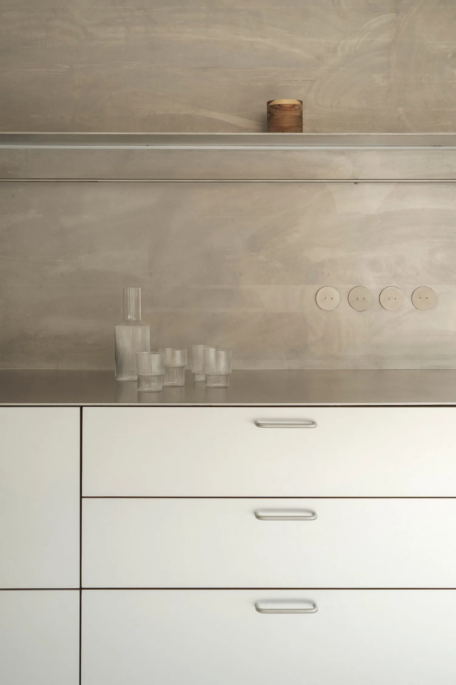 A modern kitchen featuring metallic cabinets and a concrete backsplash.