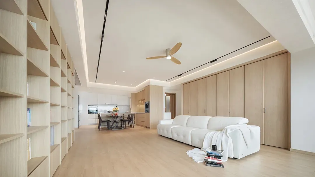 Minimalist living room featuring a white sofa, wooden shelves, and a wooden dining table.