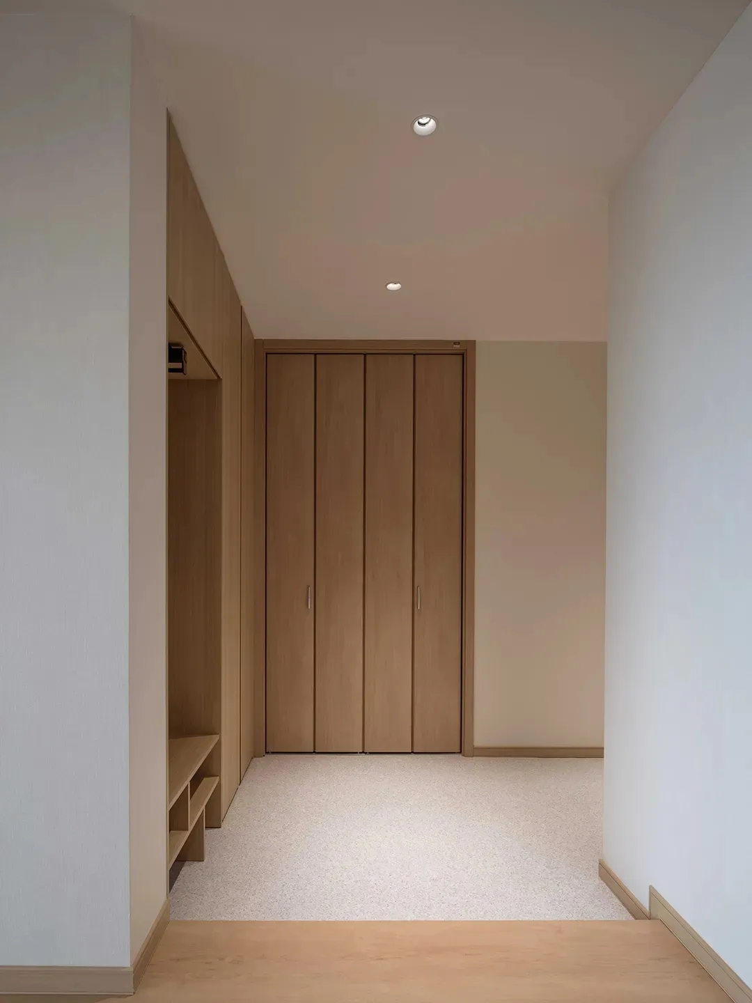A modern industrial corridor with minimalist wooden cabinets and white walls.
