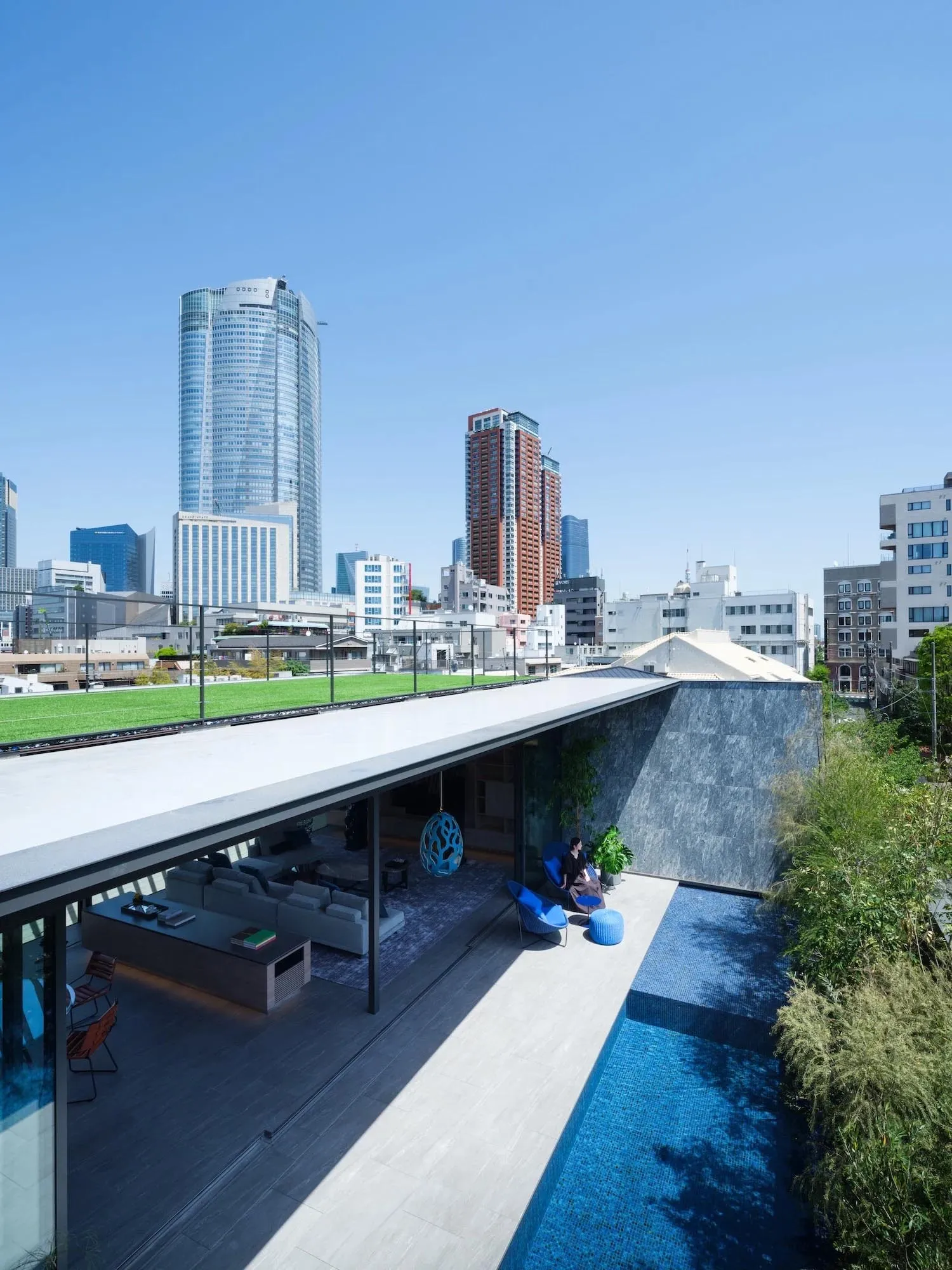 Modern residential rooftop featuring a pool and views of a city skyline.