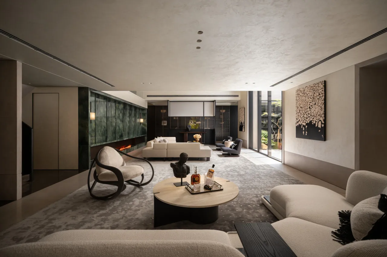 A modern living room with neutral tones and marble accents, featuring a cozy fireplace and comfortable seating.