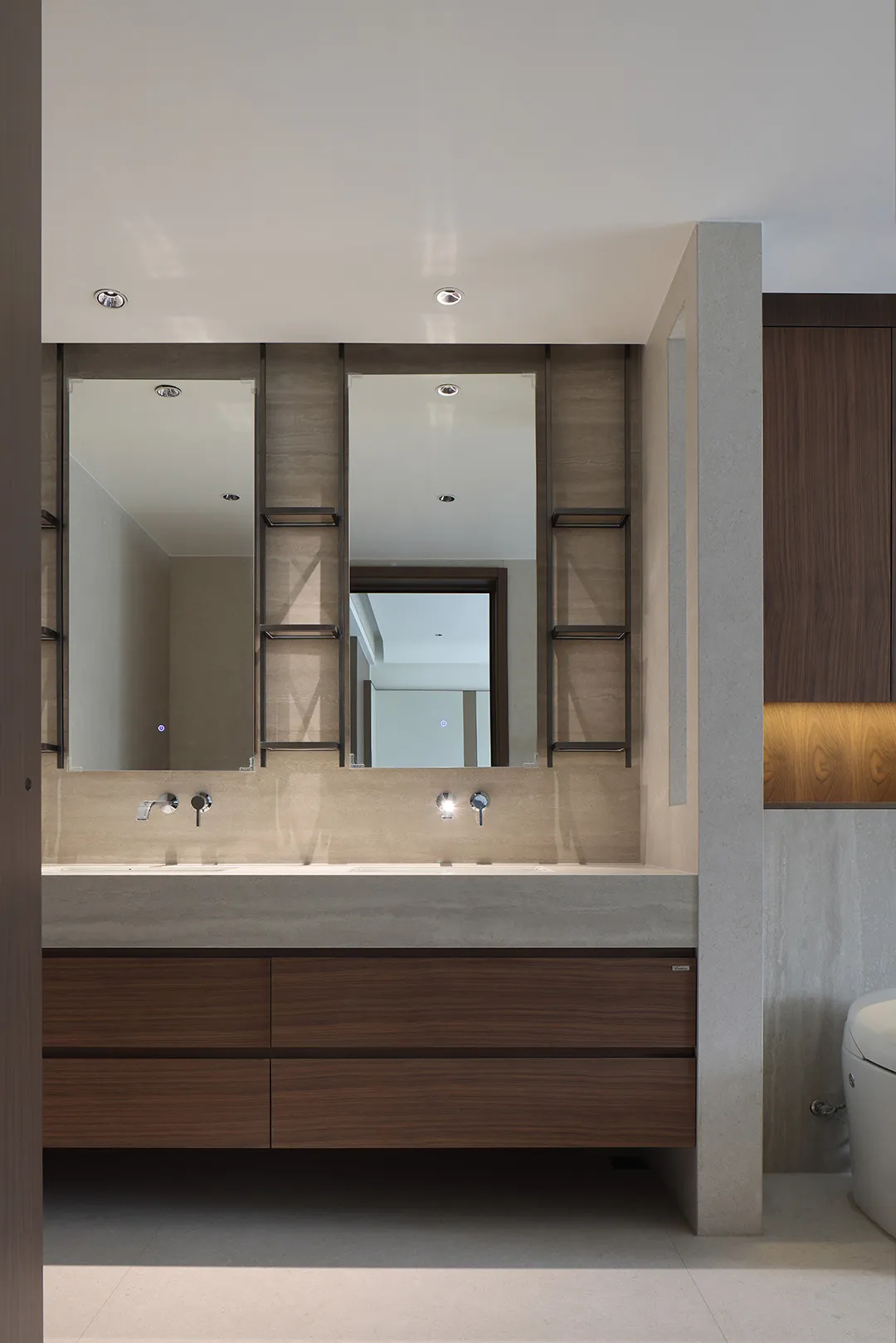 A modern bathroom with a concrete countertop and walnut storage drawers.