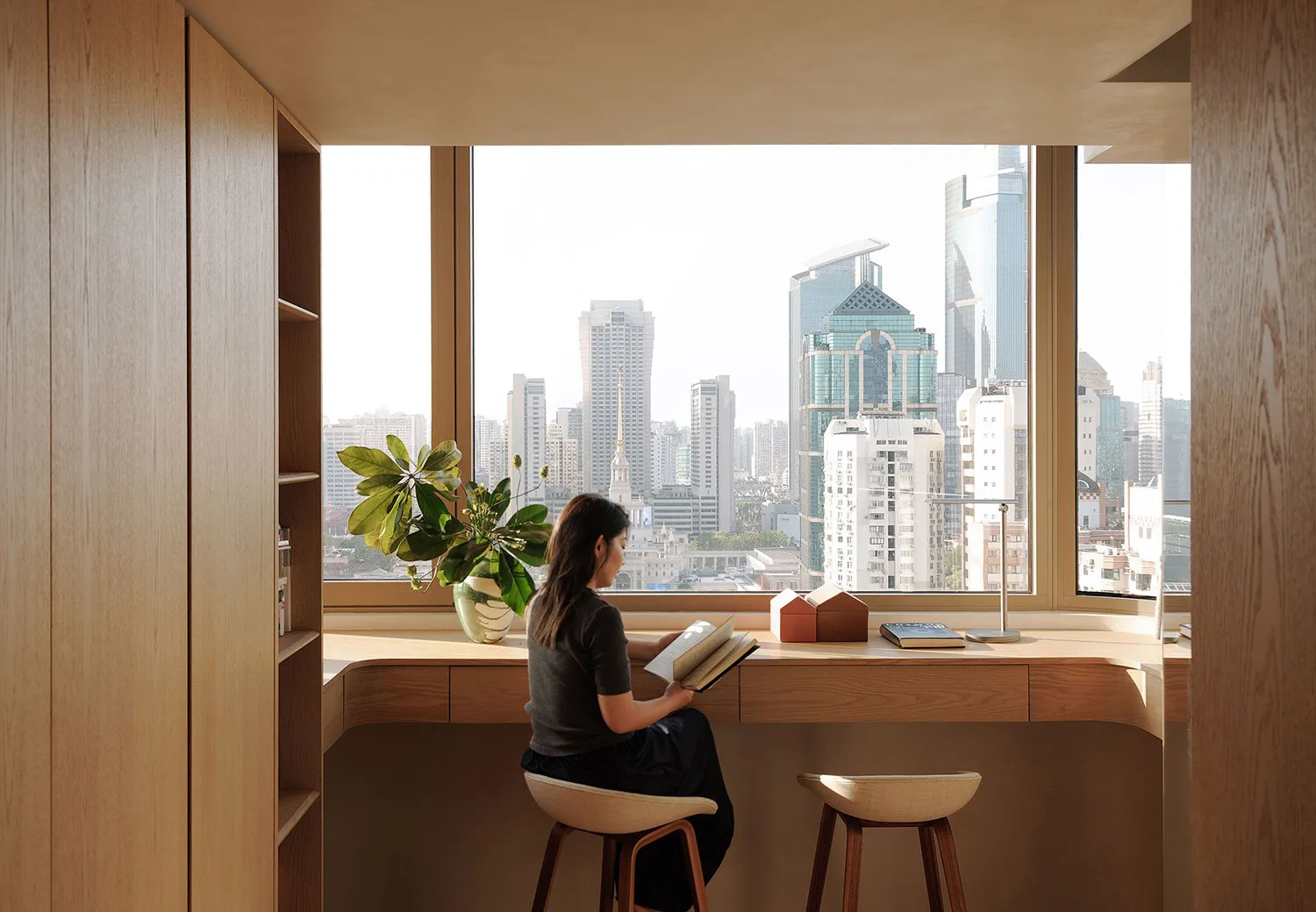 A person seated at a wooden desk in a modern office environment, overlooking a city skyline.
