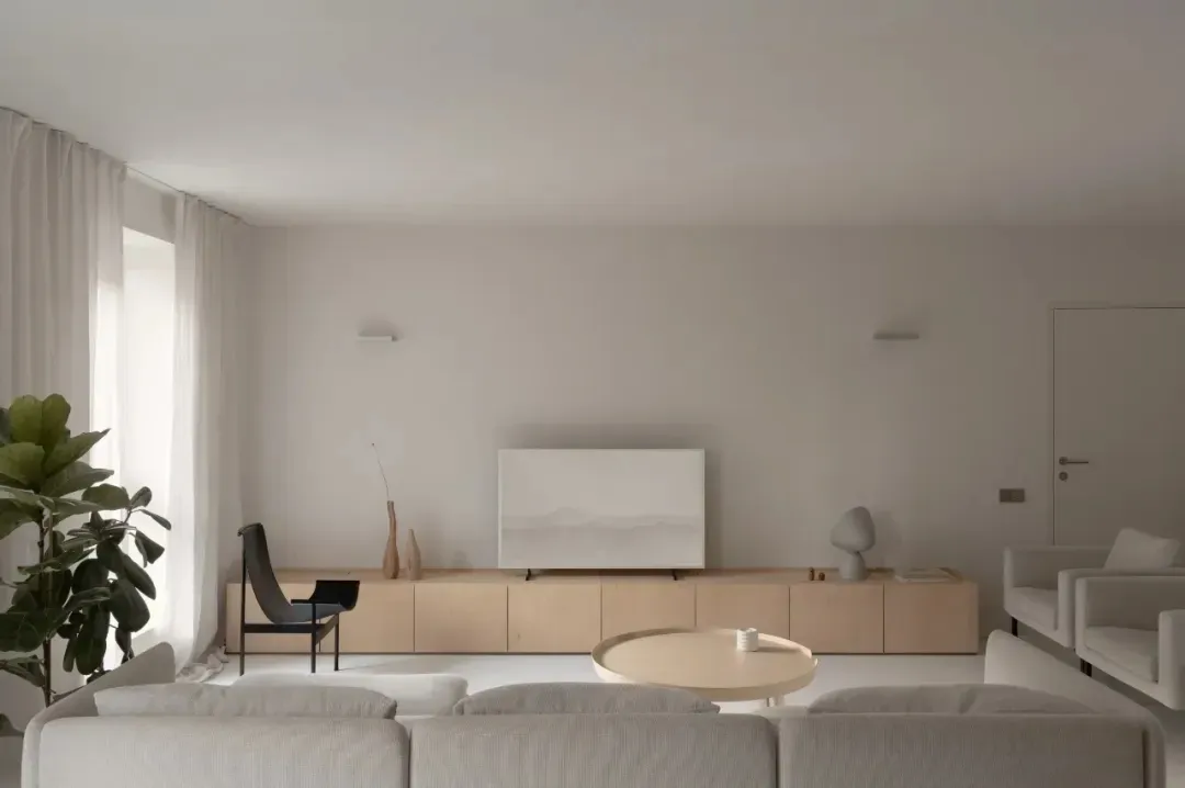 Modern minimalist living room featuring wood furniture, white walls, and a round coffee table.