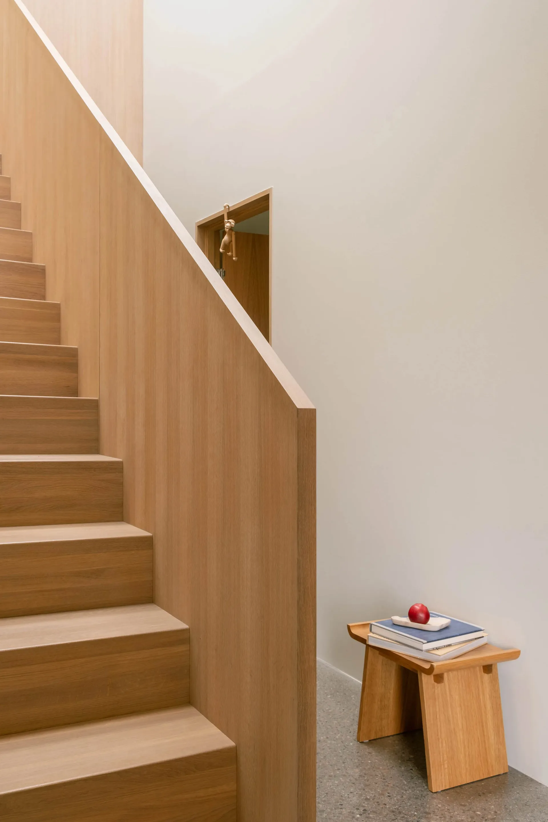 A modern staircase with wooden steps and banister against a white wall.