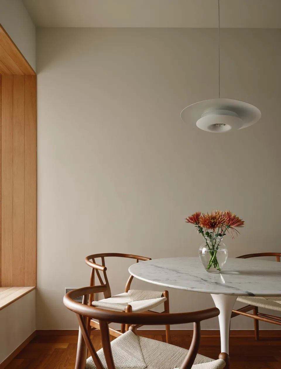 A minimalist dining room with a marble table and wooden chairs.