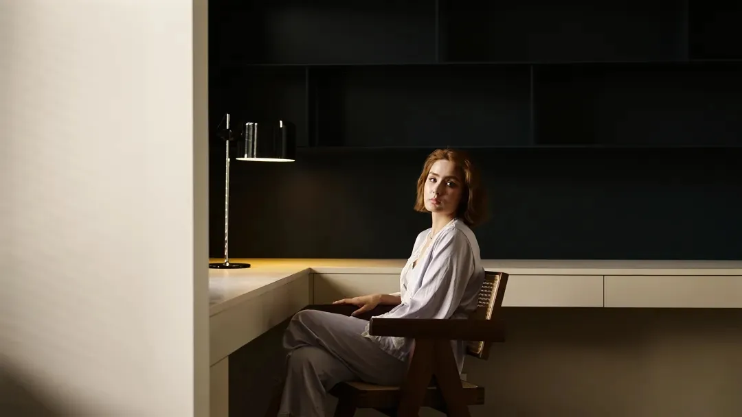 A modern desk setup featuring a wooden chair and a sleek, contemporary lamp.