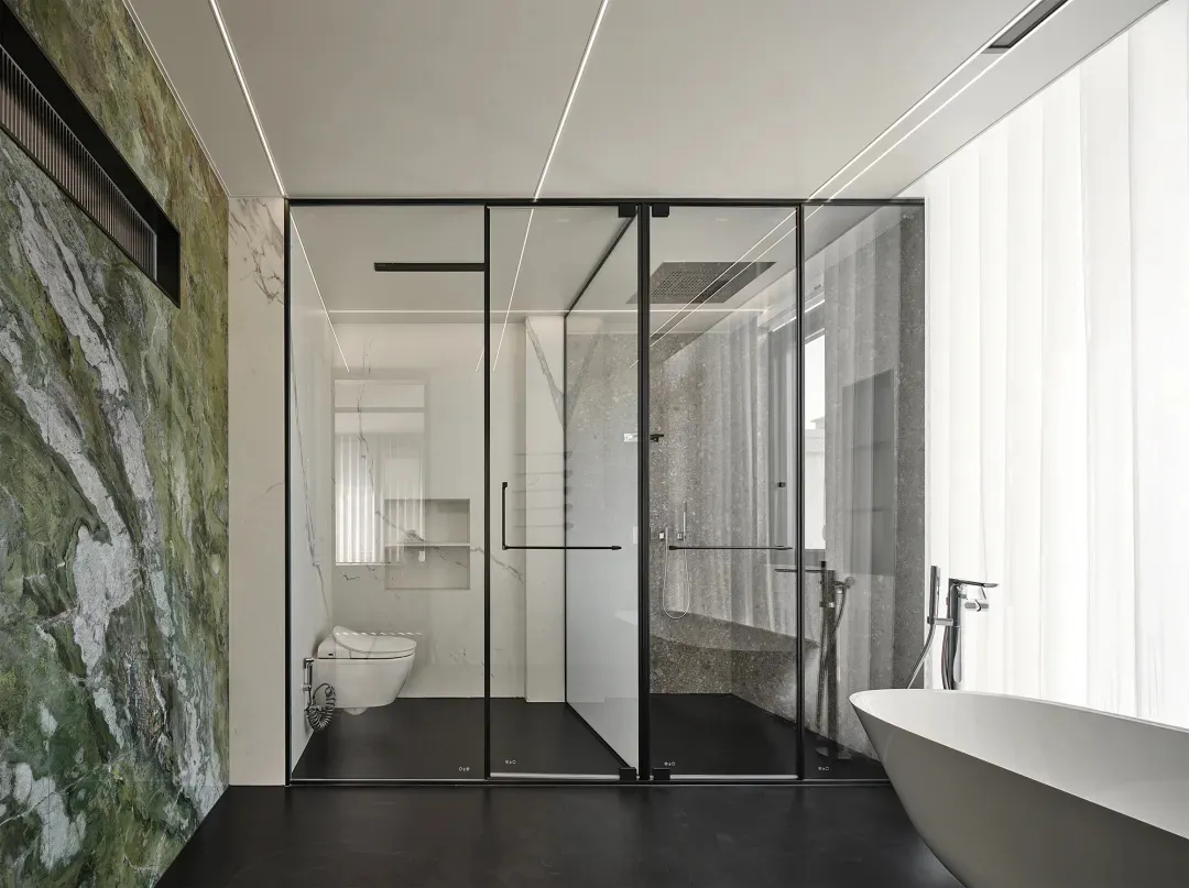Modern bathroom featuring marble walls, glass shower enclosure, and freestanding bathtub with floor-to-ceiling window.