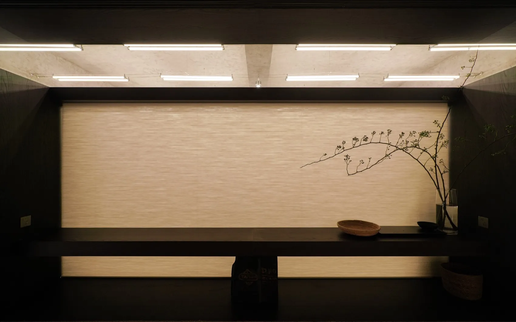 A minimalist interior design featuring blinds on a dark, wooden shelf.