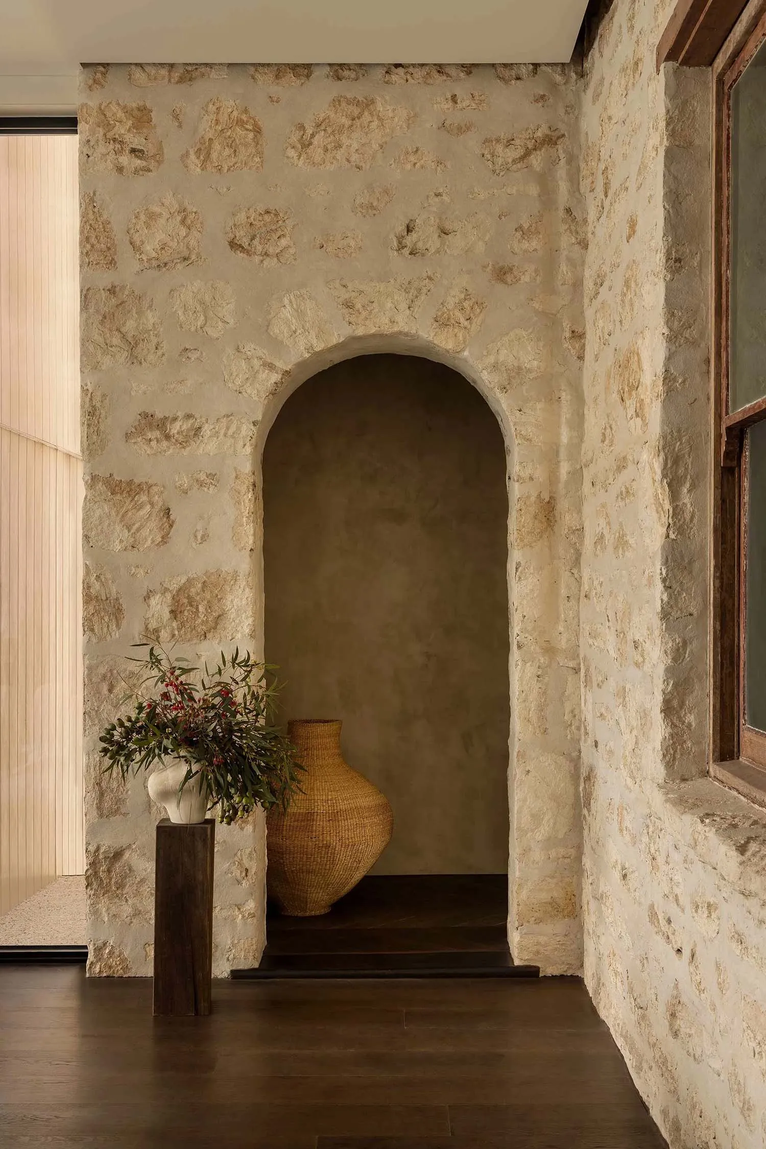 Modern entryway featuring a stone archway and a wicker basket, creating a warm and welcoming atmosphere.